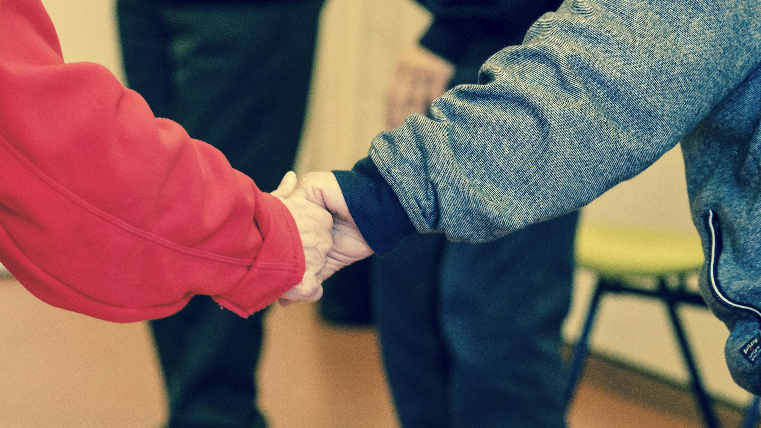 Close-up of elderly hands holding, symbolizing friendship and support indoors.